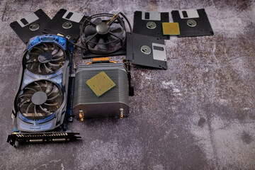 Composition of various computer components on a dark background similar to cement, different computer components such as hard drives, disk drives, graphic controller, micro chips, fans and heat sinks.