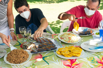 Group of friends and family members With Face Mask enjoying outdoors, having dinner together in nature