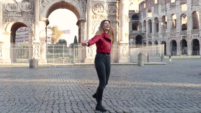 Young woman traveling to Rome. The beautiful blonde woman is dancing happily in front of the Arch of Titus.