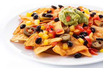 Mexican nachos tortilla chips with black beans, guacamole, tomato and jalapeno isolated on white background
