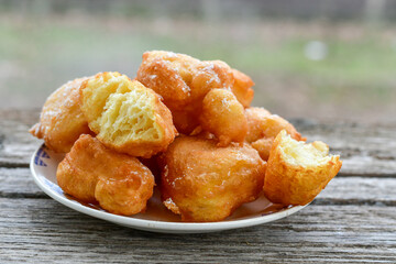Traditional Bulgarian home made deep fried  patties  covered with sugar  оn rustic backgroud.Mekitsa or Mekica,  on wooden  rustic  background. Made of kneaded dough that is deep fried 