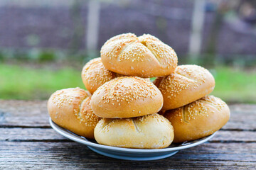 Tasty fresh  crisp  bakery product.   Baked bund bread with sesame seeds on wooden rustic background. Outdoor in a village
