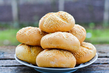 Tasty fresh  crisp  bakery product.   Baked bund bread with sesame seeds on wooden rustic background. Outdoor in a village