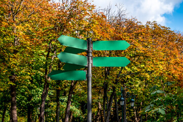 Travel signpost with several blank arrows on autumn park background. Road sign mockup © ioanna_alexa