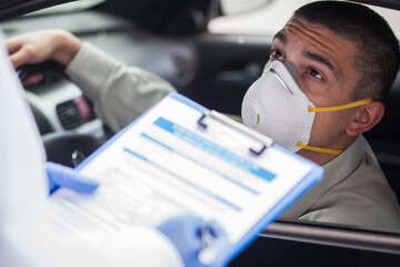 Young man wearing protective face mask in drive-thru vaccination or testing center - obrazy, fototapety, plakaty