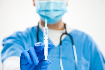 Closeup of medical worker's hands in blue gloves holding syringe with needle isolated on white background