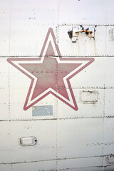 Close-up of the side of an old airplane with a red star on it
