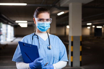 Portrait of young female emergency medical services worker on a parking lot wearing blue protective...