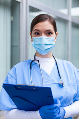 Closeup portrait of female doctor in blue uniform holding clipboard