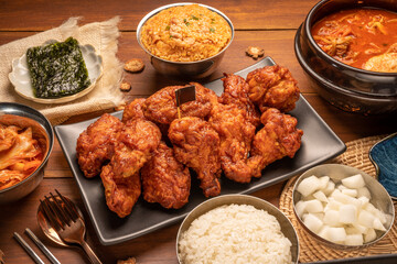 Traditional Korean food, Korean Fried chicken with spicy sauce  with rice, seaweed and Kimchi pickle on wooden table.