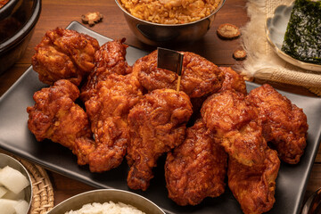 Traditional Korean food, Korean Fried chicken with spicy sauce  with rice, seaweed and Kimchi pickle on wooden table.