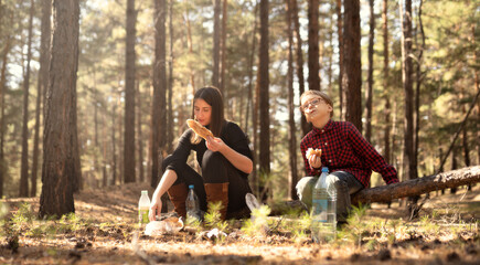 child and woman have a snack in the forest
