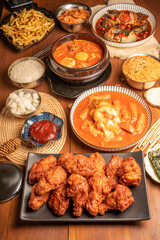 Traditional Korean food, Korean Fried chicken with spicy sauce  with rice, seaweed,fresh raw crabs marinated,spicy Rice Cake and Kimchi pickle on wooden table.