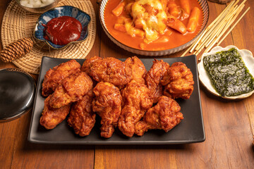 Traditional Korean food, Korean Fried chicken with spicy sauce  with rice, seaweed,fresh raw crabs marinated,spicy Rice Cake and Kimchi pickle on wooden table.