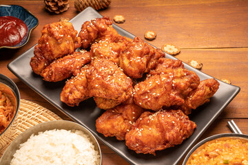 Traditional Korean food, Korean Fried chicken with spicy sauce  with rice, seaweed and Kimchi pickle on wooden table.