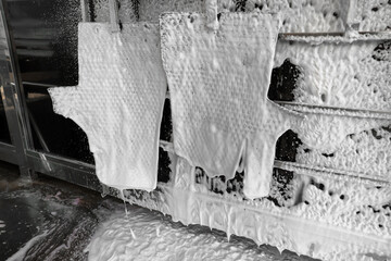 Auto mats covered with foam hanging at car wash, closeup