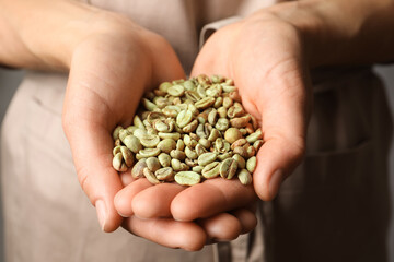 Woman holding pile of green coffee beans, closeup