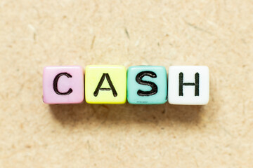 Color alphabet letter block in word cash on wood background