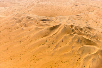 A horizontal aerial shot from an aeroplane of golden barren sand dunes, Namibian desert landscape 