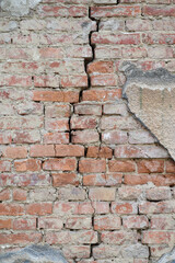 Abandoned building's wall with long crack along wall made of old red bricks on town street