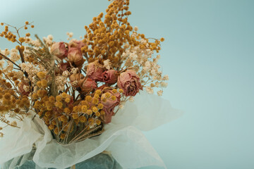 Dried flowers of yellow and pink color stand in a composition on a blue background