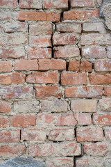 Abandoned building's wall with long crack along wall made of old red bricks on town street