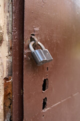 Close up old painted fitting with rusty black padlock on a worn out vintage wooden door
