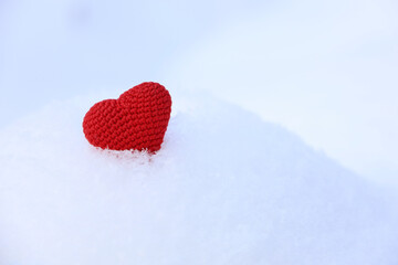 Red knitted love heart in the snow. Valentine's day card, background for Christmas or New Year celebration