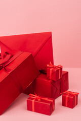 red wrapped gift boxes and envelope on pink.