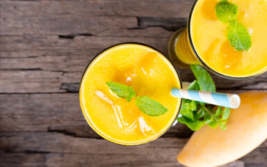 Mango smoothies orange colorful fruit juice beverage healthy high protein the taste yummy in glass on wood background from top view.
