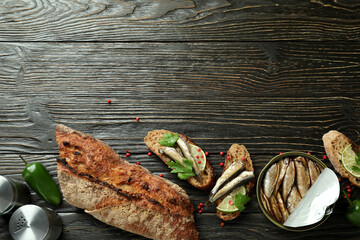 Concept of tasty snack with sandwiches with sprats on wooden background