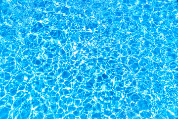 Ripple patterns from sunlight in blue water of swimming pool