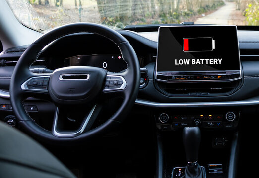Low battery warning in electric car. Red indicator on display. battery icon on plug in hybrid car.