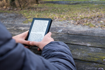 Young man reading an e-book on digital tablet device in outdoor at winter