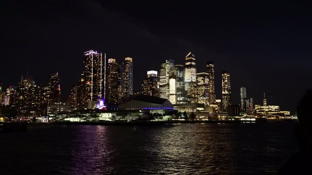 skyscrapers of Lower Manhattan in New York city, illuminated at night. Tourists take photos of it