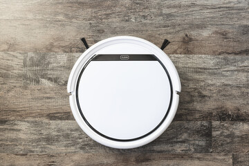 White robotic vacuum cleaner with word clean on laminat wood floor Everyday cleaning dust and pet...