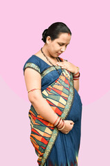 An Indian pregnant lady touching her chest and lower belly with one hand eyes closed feeling, down...