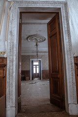 A beautiful high doorway in an old abandoned manor house. Old wooden doors. Shabby walls with mold Ancient architecture.