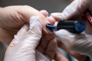 close-up of the nail on which the blue gel polish is applied with a brush