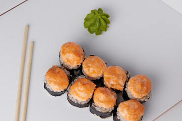 a portion of rolls on a stand, japanese food, sushi on the table, chinese chopsticks, light background