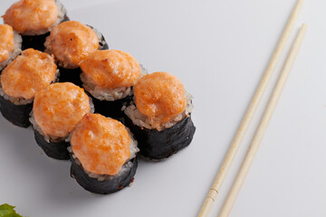 a portion of rolls on a stand, japanese food, sushi on the table, chinese chopsticks, light background