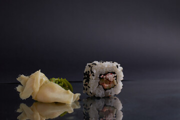 several different rolls on the table, asian food, side view, dark background, sushi, ginger and wasabi