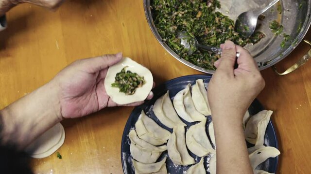 A Chinese family sitting together making dumplings