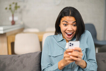 Overjoyed woman looking at phone screen, celebrating success. Excited satisfied young female holding smartphone, reading good news in message, lottery win, shopping offer