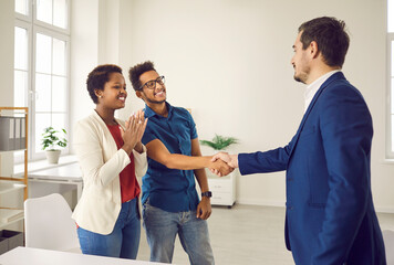 Real estate agent shake hand of excited couple congratulate with home purchase or buy. Realtor or broker handshake buyers or clients greeting with house ownership. Rental, realty concept. - obrazy, fototapety, plakaty