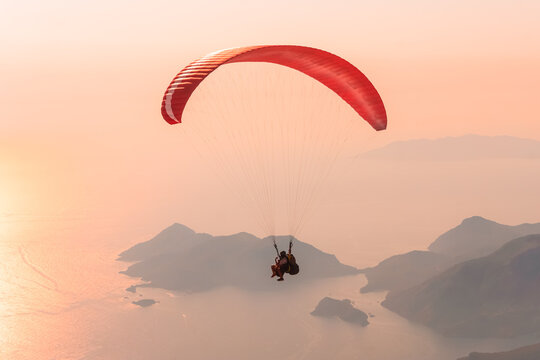 Sunset landscape with paragliding in the sky. Paraglider tandem flying over the Mediterranean sea at sunset.
