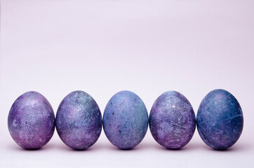 Easter eggs in trendy purple very peri color. Chicken eggs stand in a row on pink. Natural dye karkade tea.