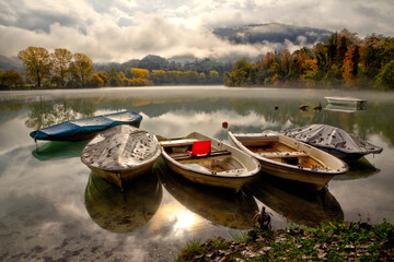 Fototapeta premium Fishing boats on lake in a foggy autumn morning