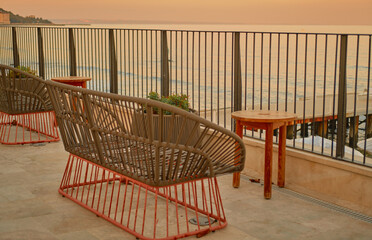 Empty wicker chairs and table with sea and sunset views. 