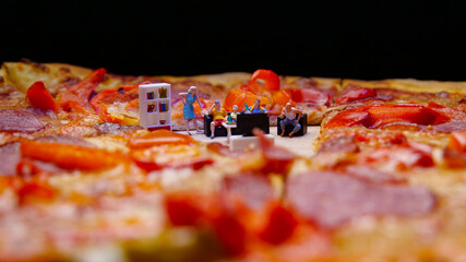 Miniature family watching TV inside pizza. Conceptual image. Watching match with friends, eating...